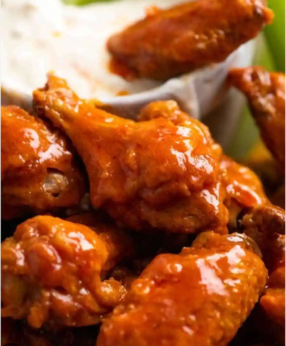 A bowl of buffalo wings with dipping sauce.