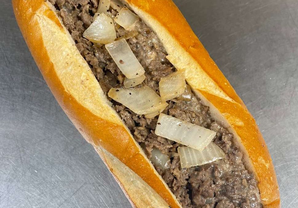 A long sandwich with meat and onions on it.